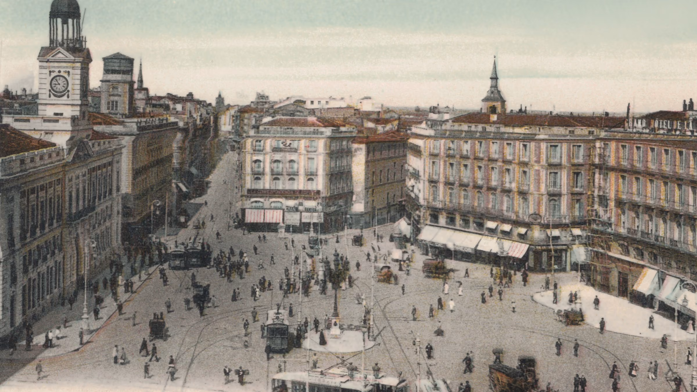 La Puerta del Sol a comienzos del siglo XX, atravesada por tranvías, coches de caballos y raíles, con la torre del reloj de la Casa de Correos al fondo